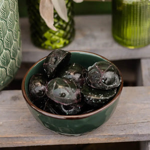 Green ceramic bowl filled with fresh, frozen spirulina on a wooden surface