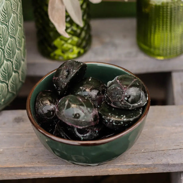 Green ceramic bowl filled with fresh, frozen spirulina on a wooden surface