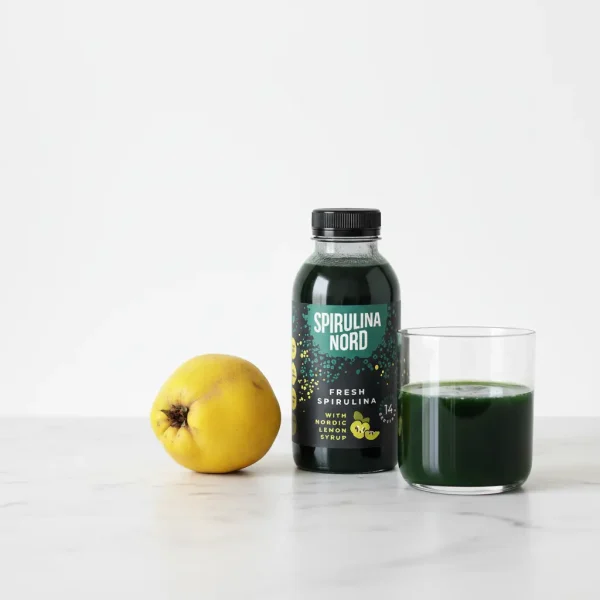Quinc, and a bottle of fresh, liquid spirulina placed on a kitchen countertop
